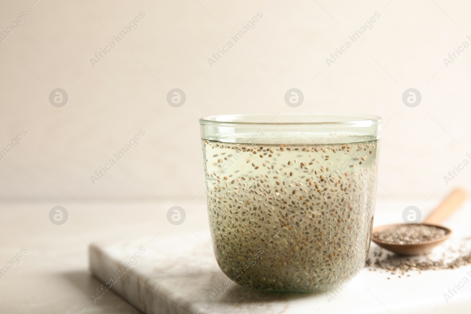 Photo of Glass of water with chia seeds and spoon on board, space for text