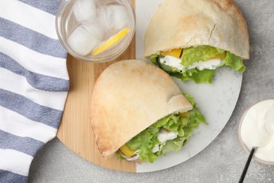 Photo of Delicious pita sandwiches with chicken breast and vegetables on light gray table, flat lay