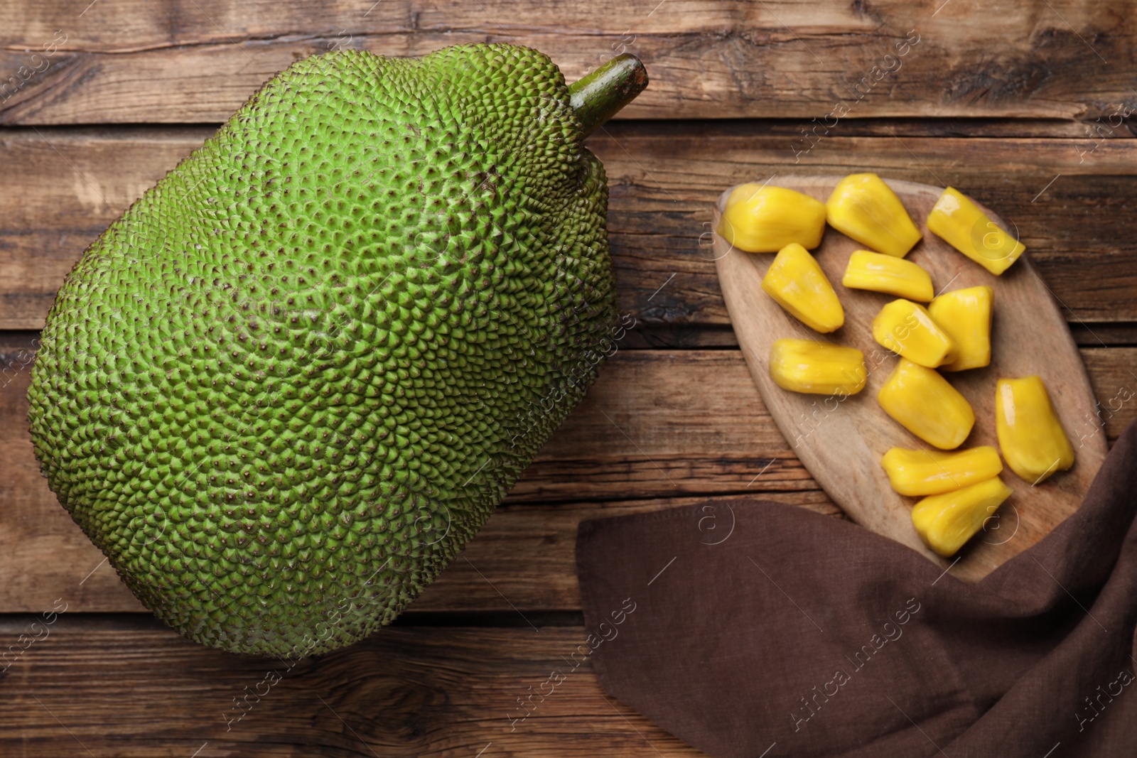 Photo of Fresh exotic jackfruit and bulbs on wooden table, flat lay