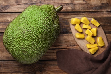 Fresh exotic jackfruit and bulbs on wooden table, flat lay