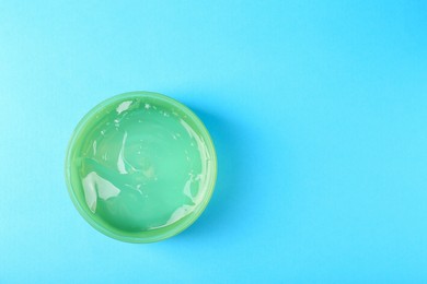 Aloe gel in jar on light blue background, top view. Space for text