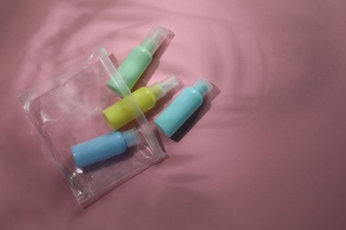 Photo of Cosmetic travel kit in compact toiletry bag on pink background, flat lay with space for text. Bath accessories