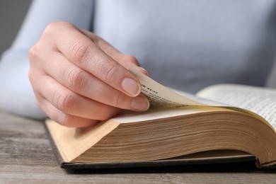 Woman reading Bible at wooden table, closeup