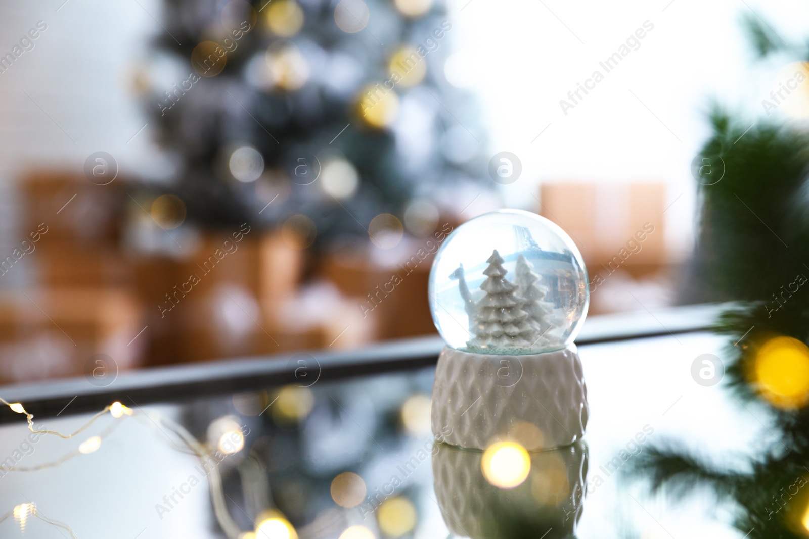 Photo of Decorative Christmas snow globe on mirror surface indoors