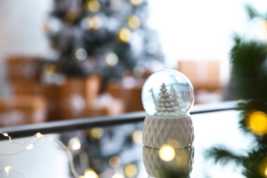 Decorative Christmas snow globe on mirror surface indoors