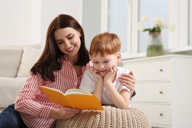 Photo of Happy mother reading book with her child at home, space for text