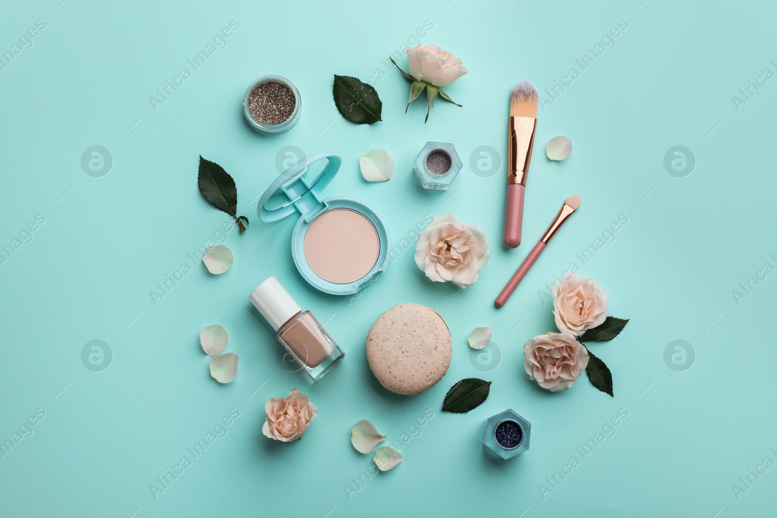 Photo of Flat lay composition with makeup products, roses and macaron on turquoise background
