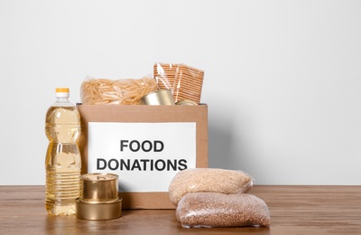 Photo of Donation box with food on wooden table