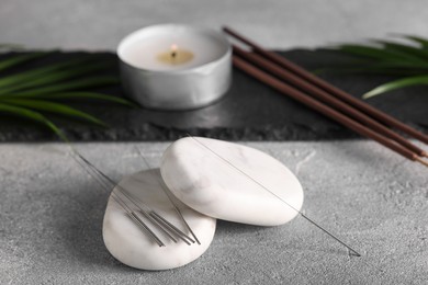 Acupuncture needles and spa stones on grey table
