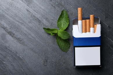 Photo of Pack of menthol cigarettes and mint on grey table, flat lay. Space for text