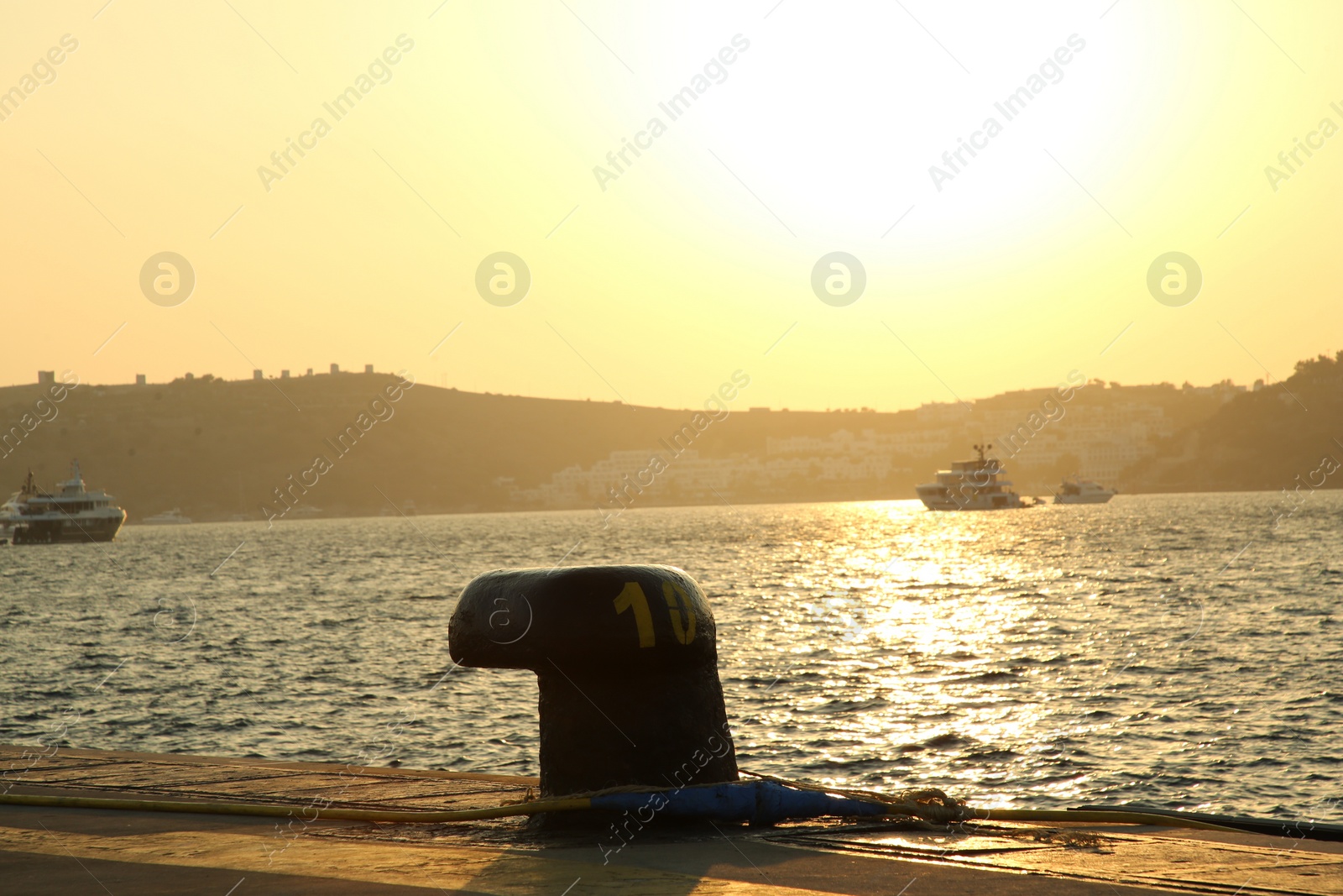 Photo of Mooring pole with rope in sea port at sunset