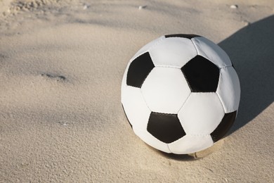 Soccer ball on sand, space for text. Football equipment