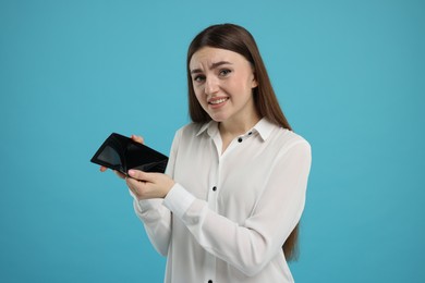 Photo of Woman showing empty wallet on light blue background