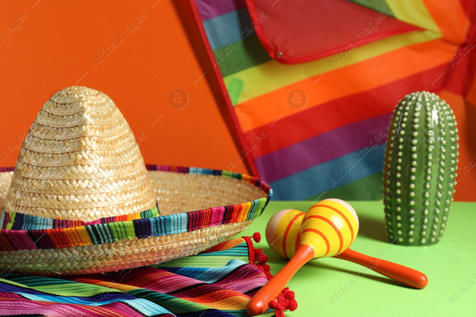 Photo of Composition with Mexican sombrero hat and maracas on green table, closeup