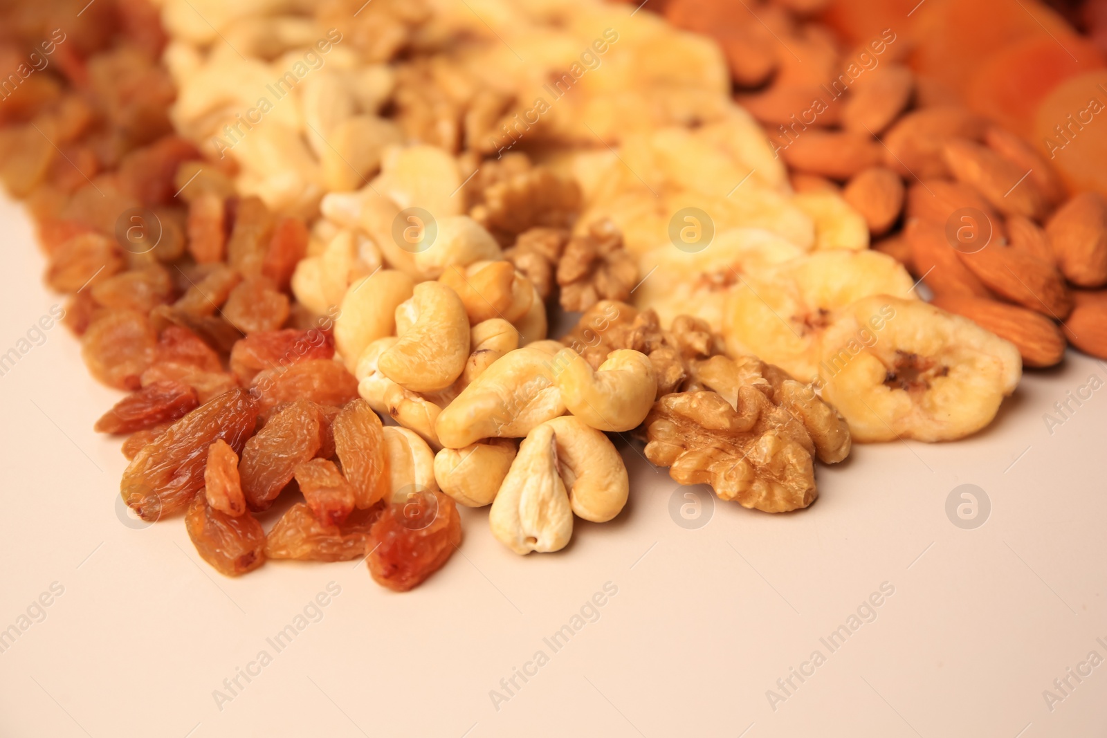 Photo of Mix of delicious dried nuts and bananas on beige background, closeup