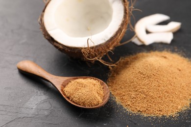 Coconut sugar, spoon and fruit on dark textured table, closeup