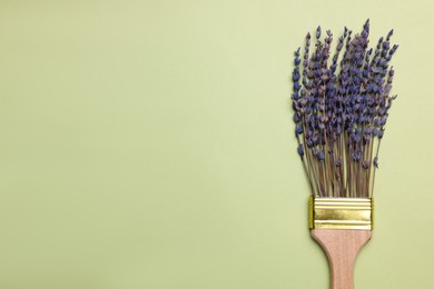 Creative flat lay composition with paint brush and lavender flowers on light green background. Space for text
