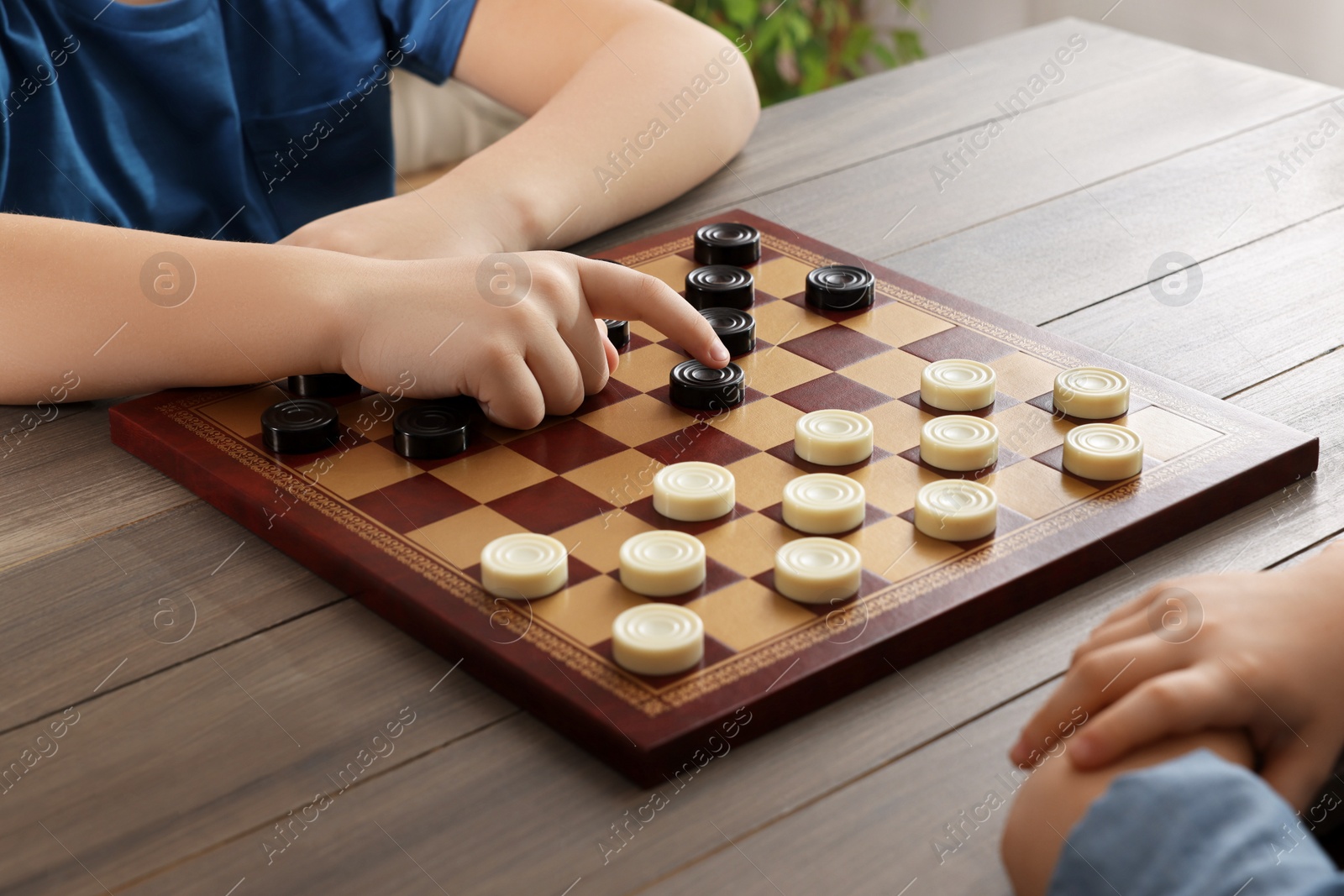 Photo of Children playing checkers at table in room, closeup