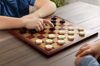 Children playing checkers at table in room, closeup