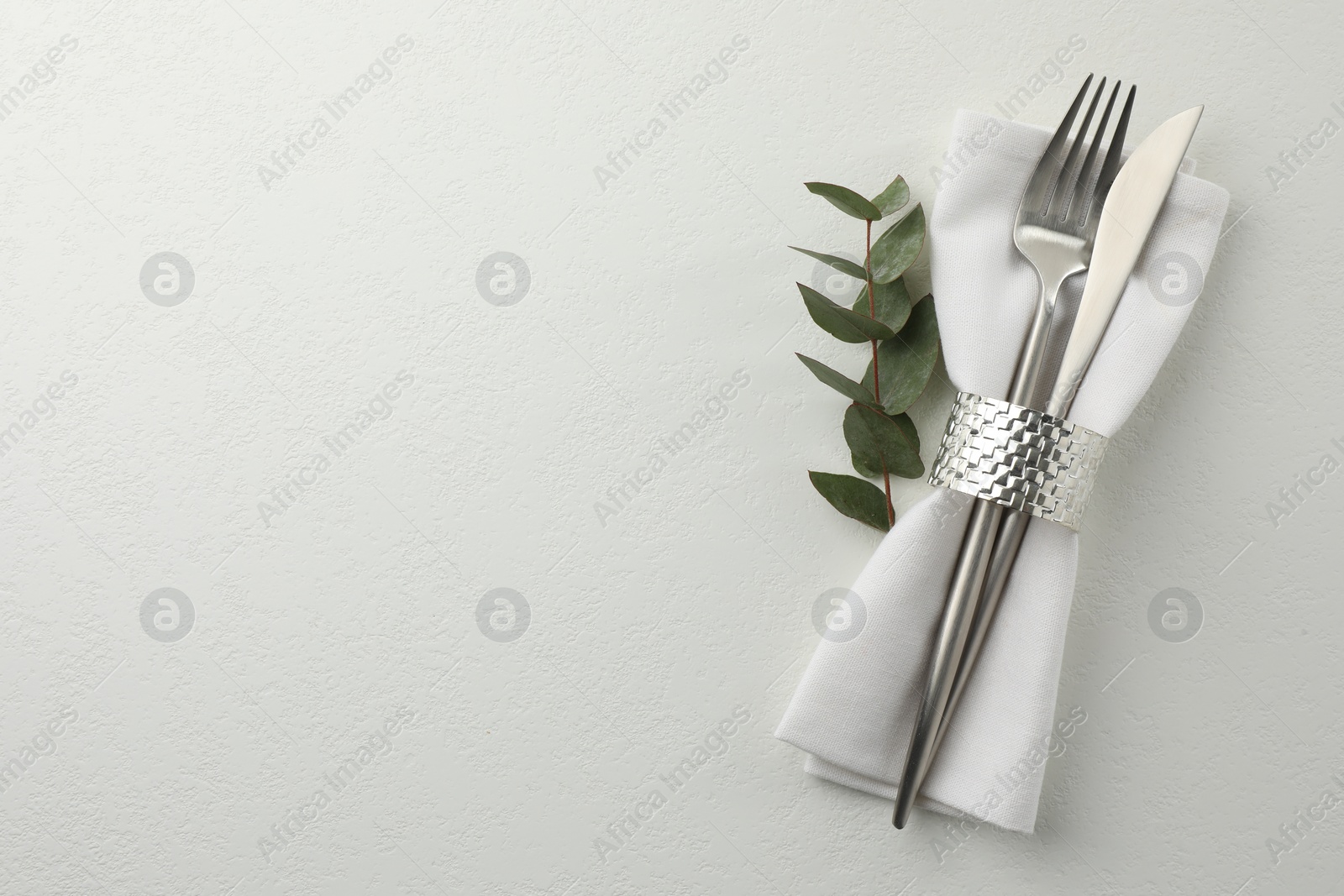 Photo of Stylish setting with cutlery and napkin on white textured table, top view. Space for text