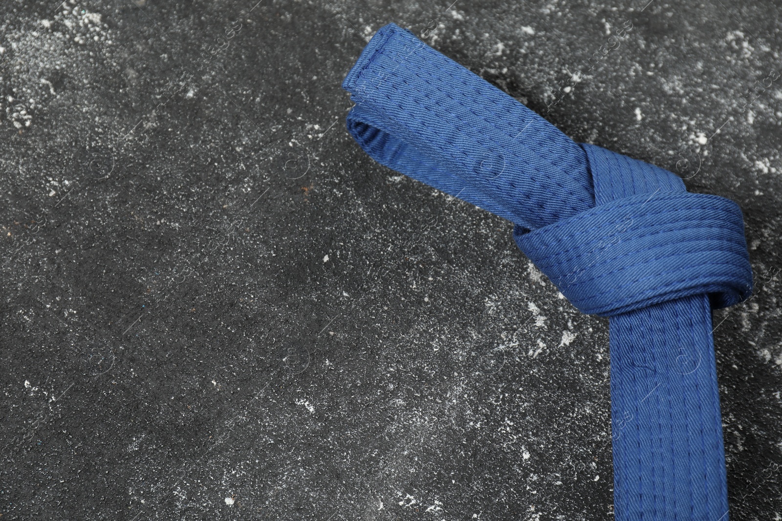 Photo of Blue karate belt on gray textured background, top view. Space for text