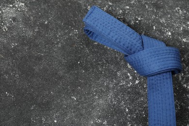 Photo of Blue karate belt on gray textured background, top view. Space for text