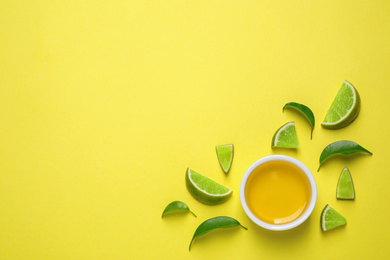 Flat lay composition with lime essential oil on yellow background. Space for text