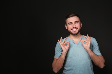Photo of Man showing OK gesture in sign language on black background, space for text