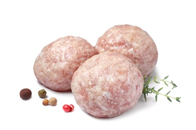 Photo of Three fresh raw meatballs with thyme and spices on white background