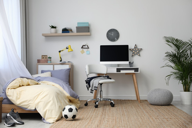 Stylish teenager's room interior with comfortable bed and workplace