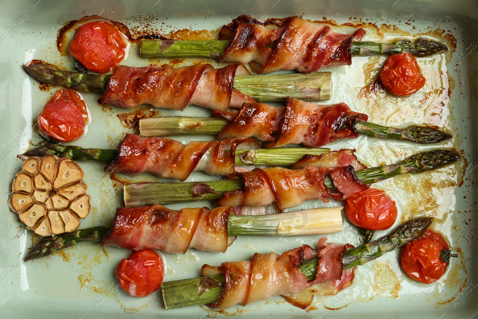 Photo of Oven baked asparagus wrapped with bacon in ceramic dish, top view