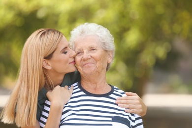 Photo of Woman with elderly mother outdoors on sunny day