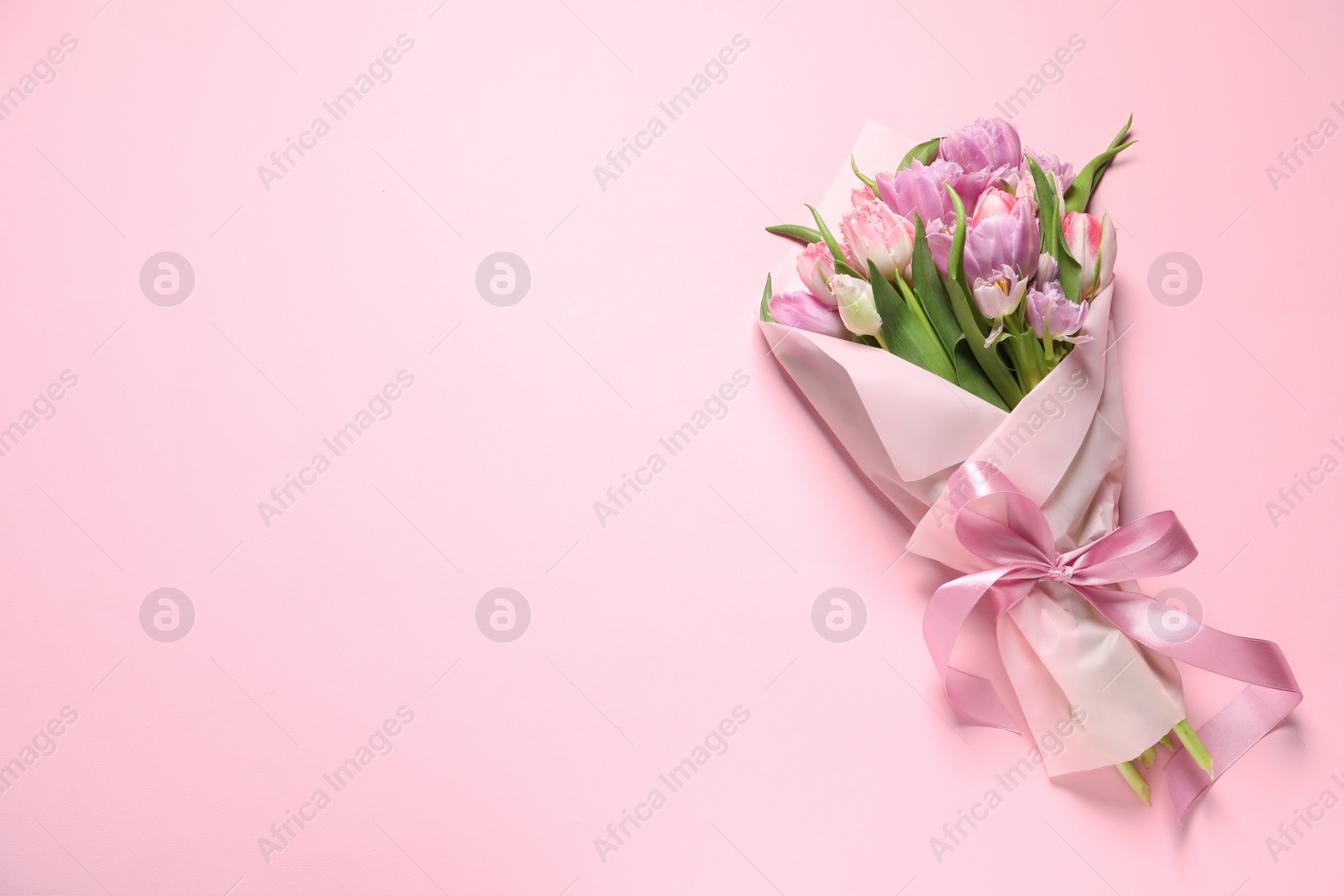 Photo of Beautiful bouquet of colorful tulip flowers on pink background, top view. Space for text