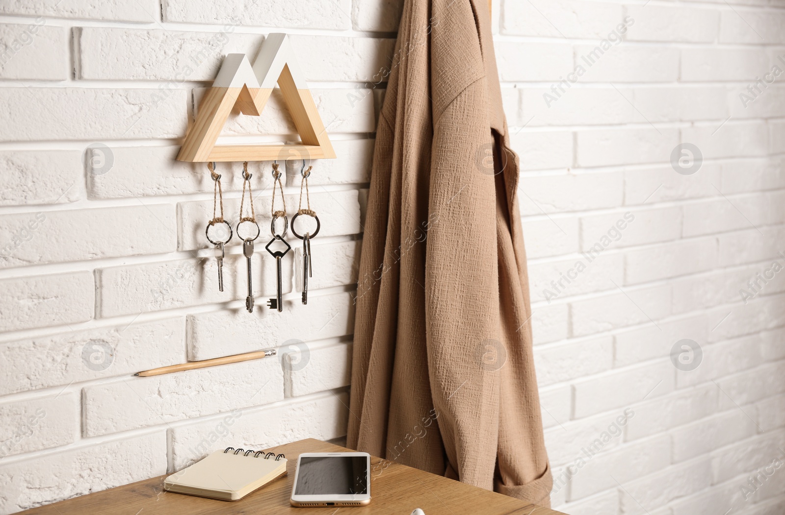 Photo of Wooden key holder on white brick wall indoors