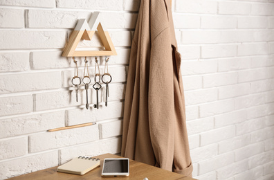 Photo of Wooden key holder on white brick wall indoors