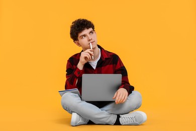 Photo of Portrait of student with laptop and pen on orange background