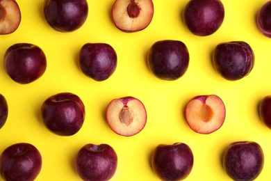 Delicious ripe plums on yellow background, flat lay