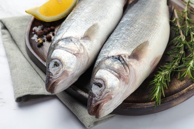 Photo of Tasty sea bass fish and spices on white marble table, closeup