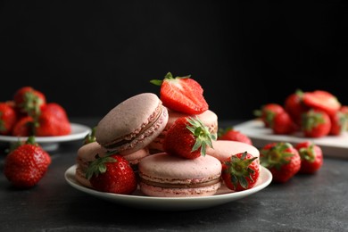 Delicious macarons and strawberries on black table