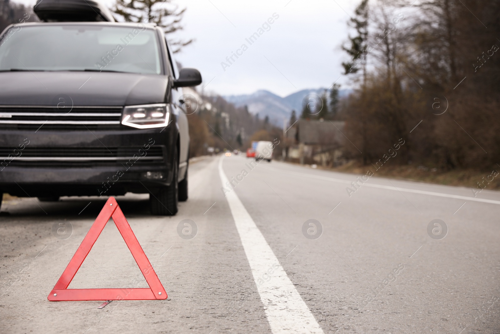 Photo of Emergency stop sign and broken car on road. Winter day