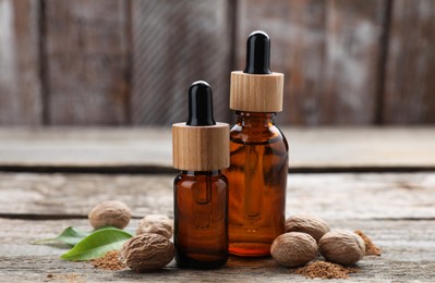 Photo of Bottles of nutmeg oil, nuts and powder on wooden table