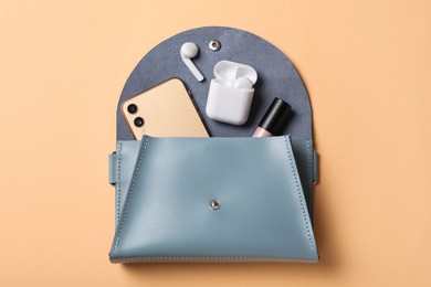 Photo of Stylish women's bag and different stuff on pale orange background, top view