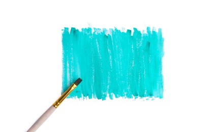 Photo of Turquoise paint strokes and brush on white background, top view