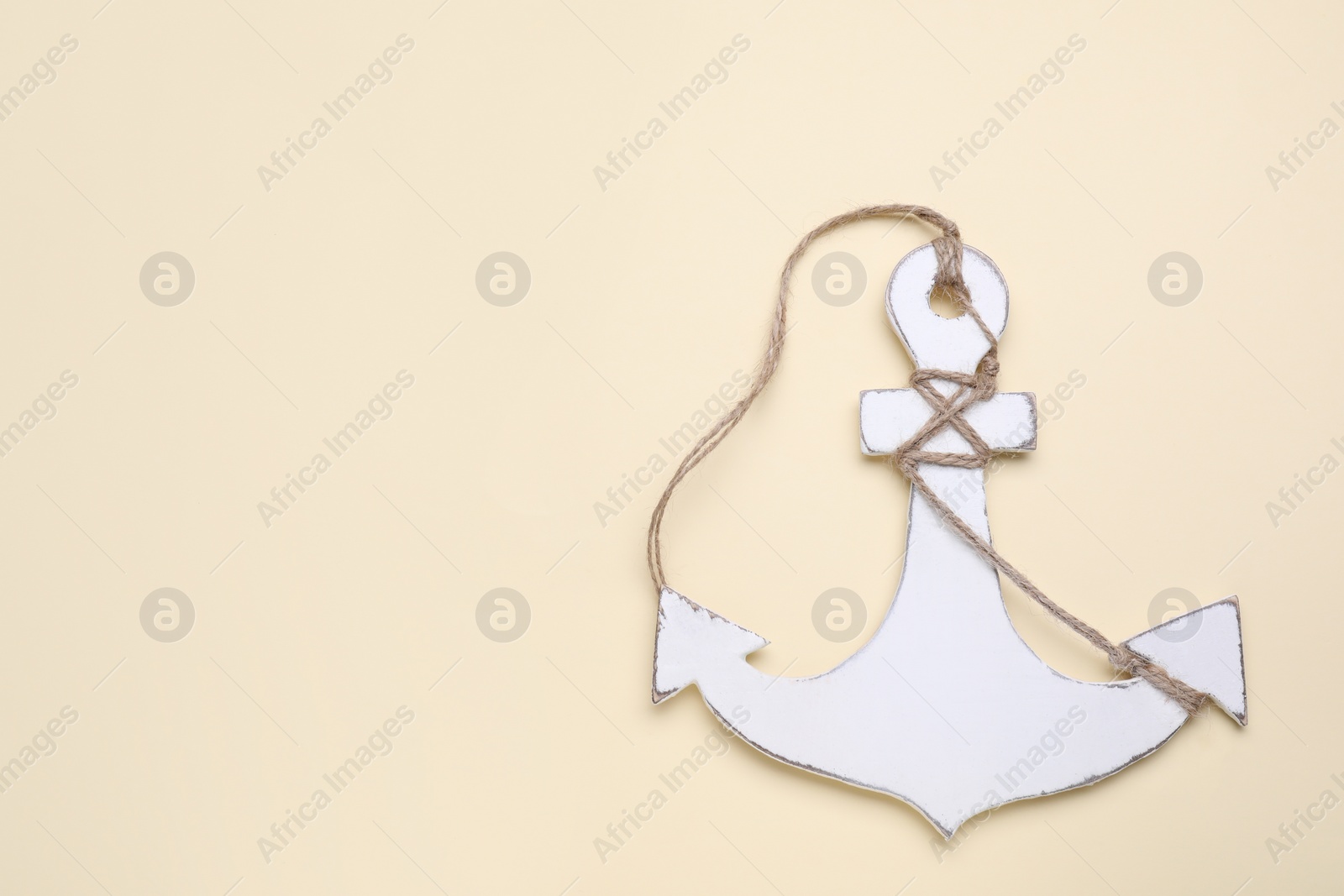 Photo of White anchor with hemp rope on beige background, top view. Space for text