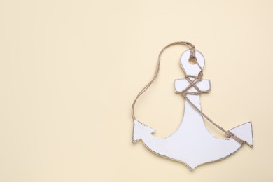 Photo of White anchor with hemp rope on beige background, top view. Space for text