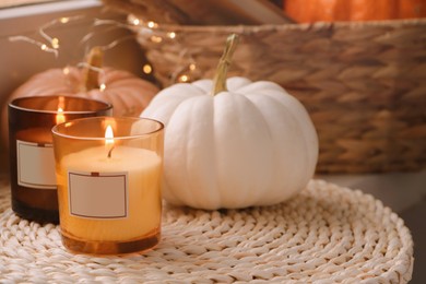 Photo of Scented candles and pumpkins on wicker mat indoors