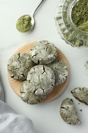 Photo of Board with tasty matcha cookies and powder on white table, flat lay