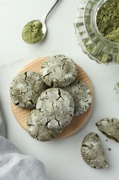 Board with tasty matcha cookies and powder on white table, flat lay