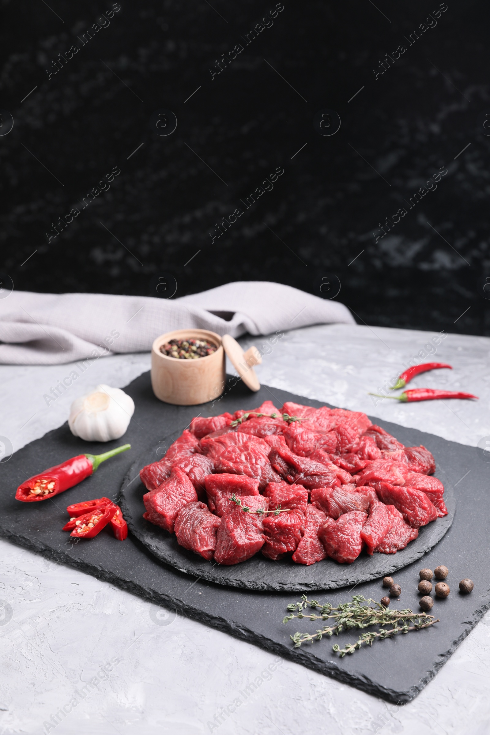 Photo of Pieces of raw beef meat, products and spices on grey textured table