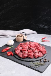 Pieces of raw beef meat, products and spices on grey textured table